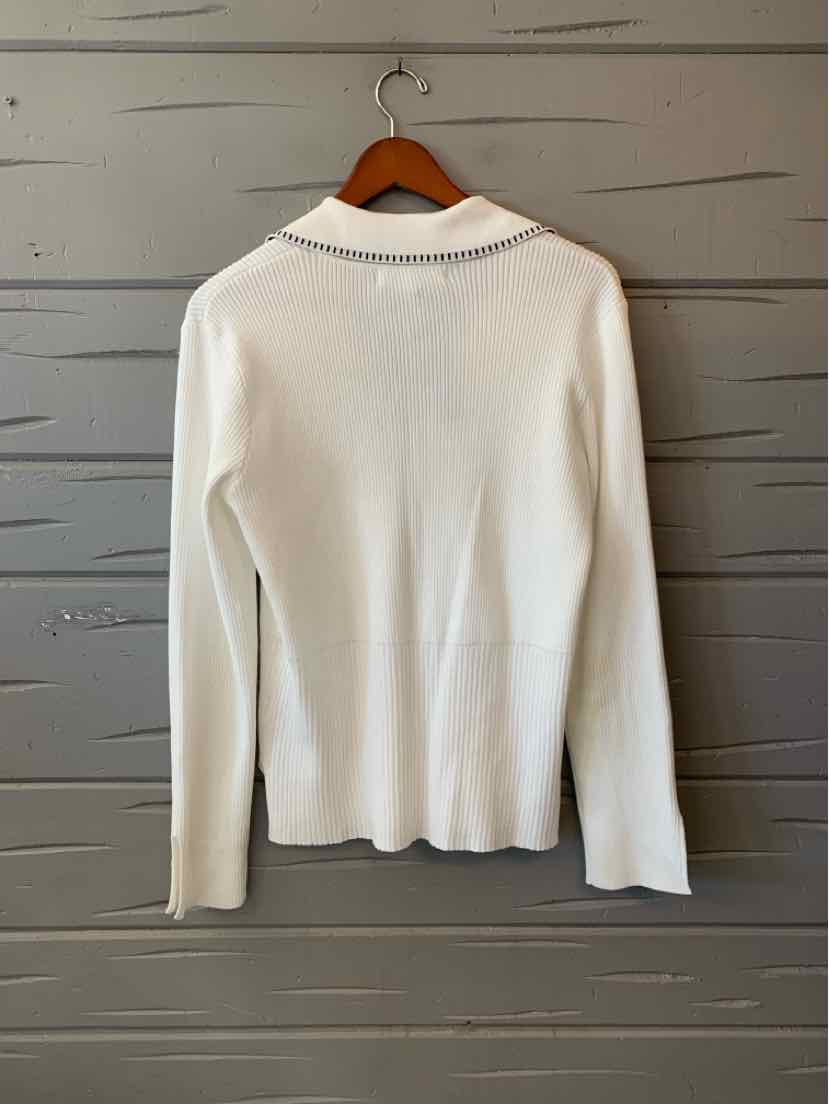 White long-sleeve knit sweater with a collar, hanging on a wooden hanger against a gray wooden wall.