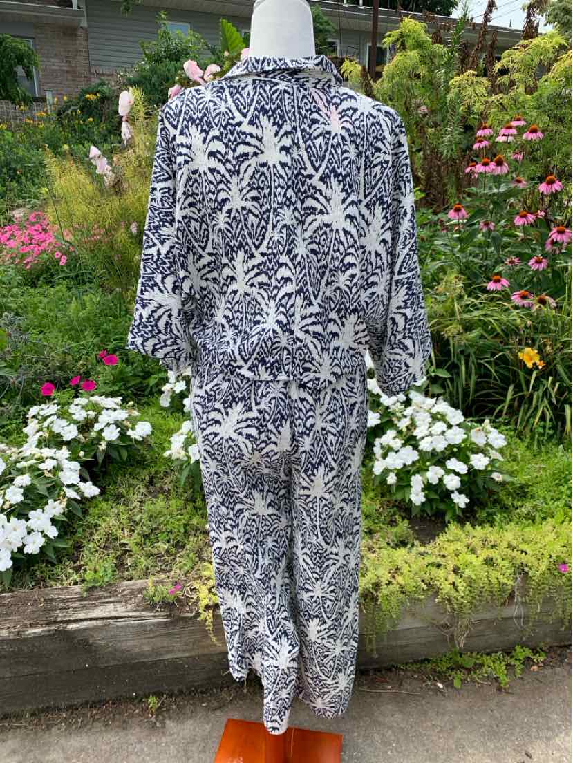 Women's tropical print jumpsuit in navy and white with long sleeves and a ruffled collar.