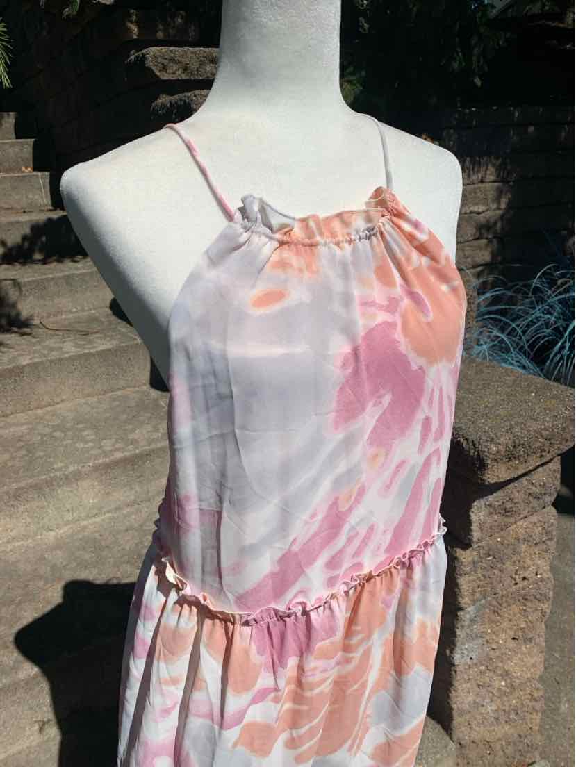 Sleeveless dress with pink and orange tie-dye pattern, halter neckline, and ruffled waist detail.