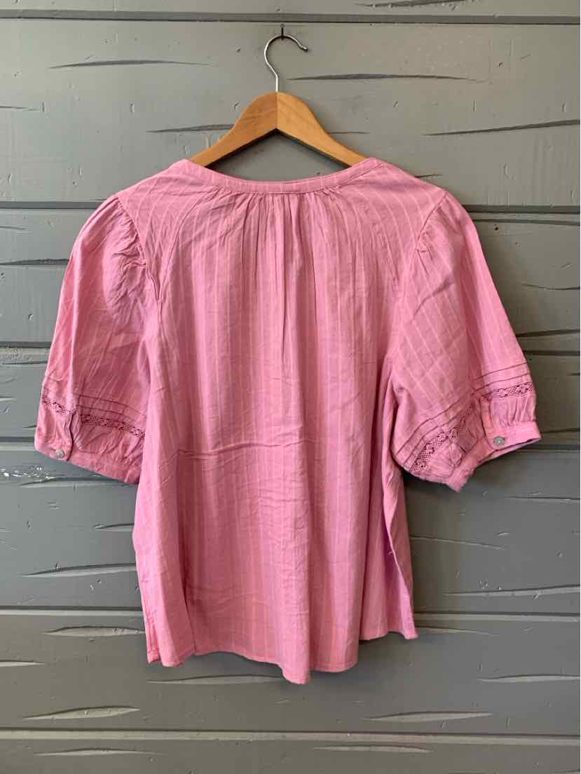 Light pink short-sleeve blouse with loose fit and gathered back yoke detail on wooden hanger.