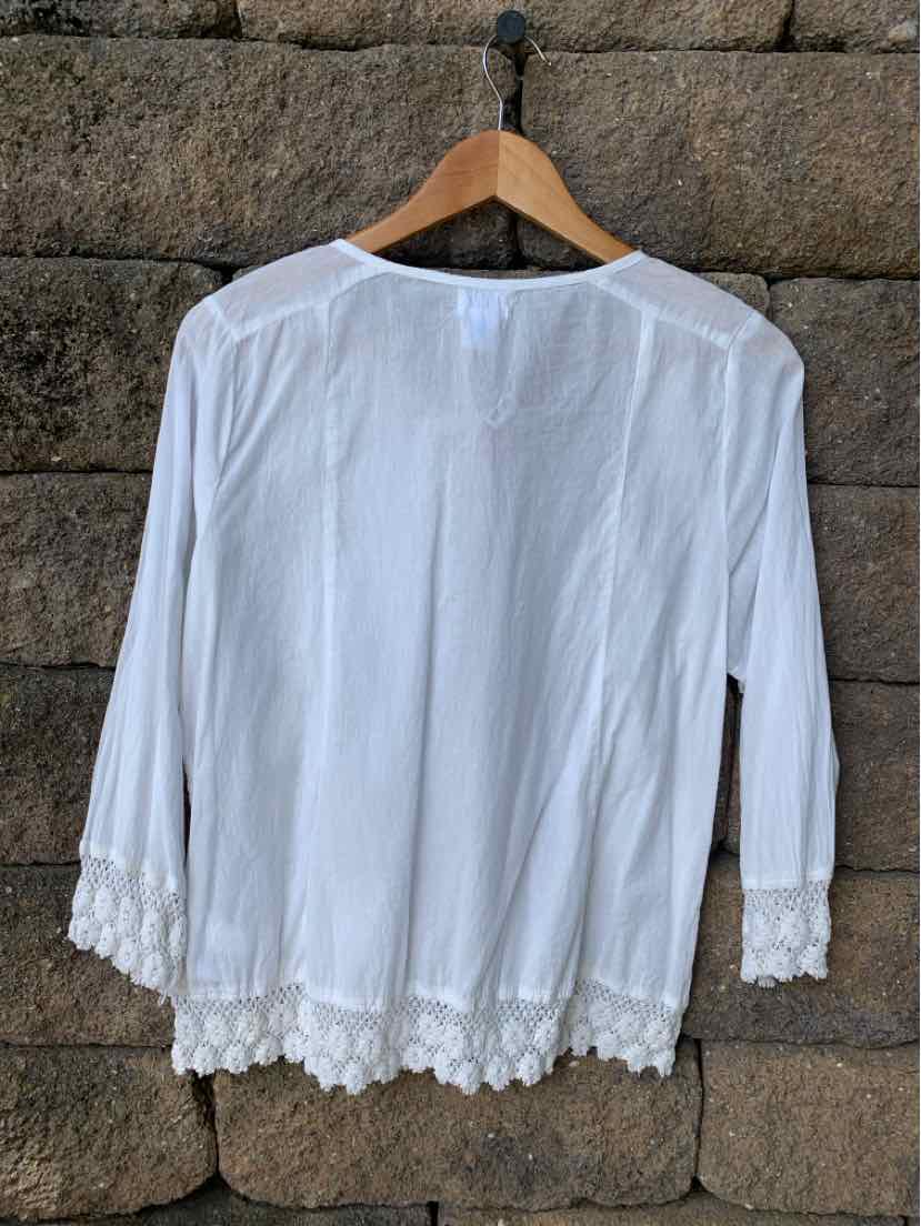 White long-sleeve blouse with scalloped lace trim on cuffs and hem, lightweight fabric.