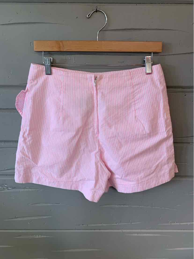 Pink striped shorts with rolled cuffs and back pockets hanging on wooden hanger.