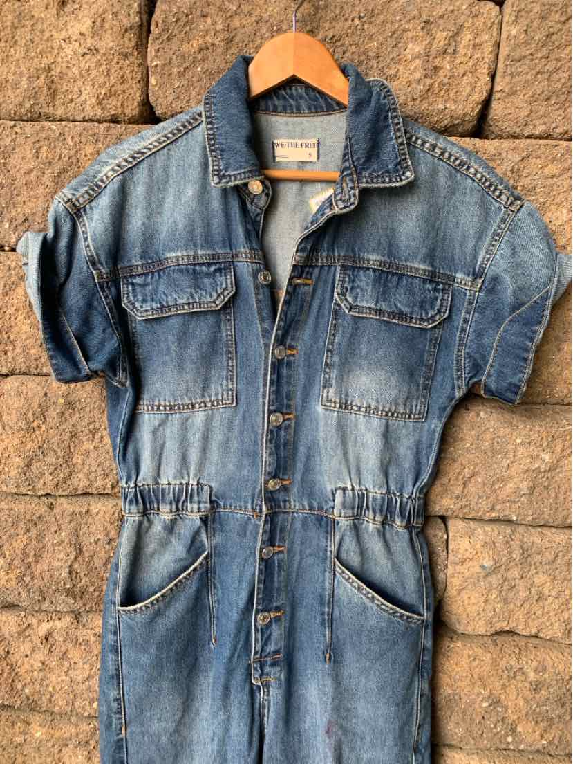 Short-sleeve blue denim jumpsuit with button front, chest flap pockets, and elastic waist.