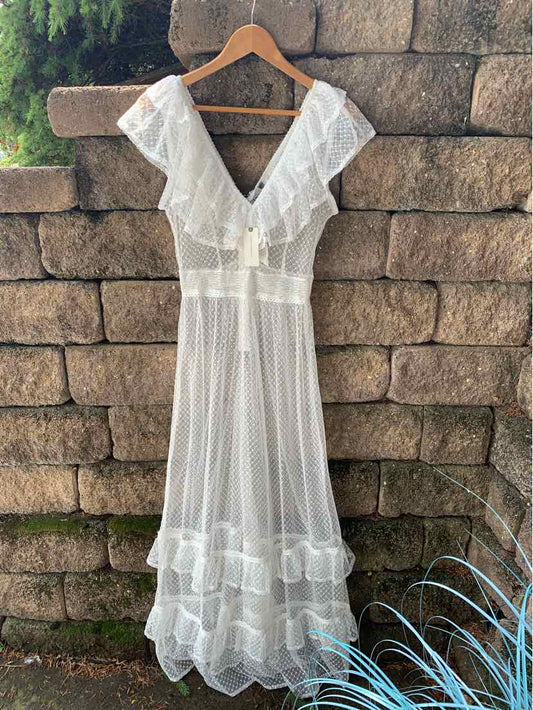 White short-sleeve dress with ruffled V-neck and tiered skirt on wooden hanger.