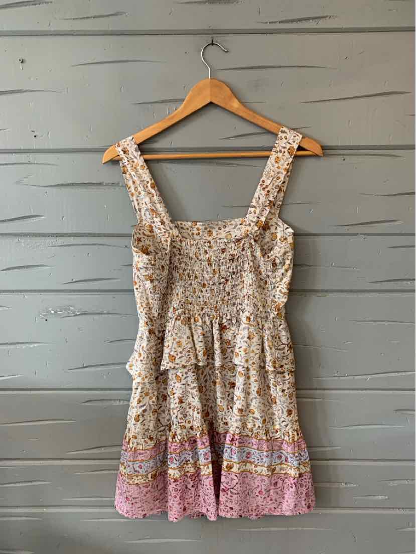 Floral sleeveless dress with wide straps, smocked bodice, and tiered skirt in soft beige and pink tones.