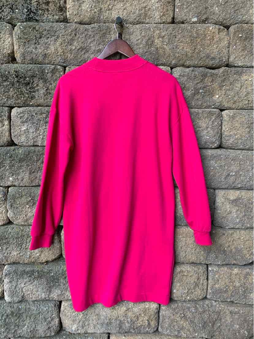 Bright pink long-sleeve sweater dress with a round neckline and relaxed fit hanging on a wooden hanger.