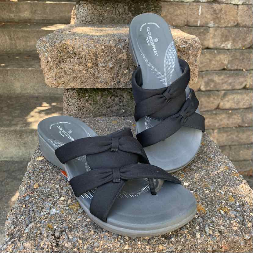 Black slip-on sandals with crisscross fabric straps and cushioned footbed, size 9.