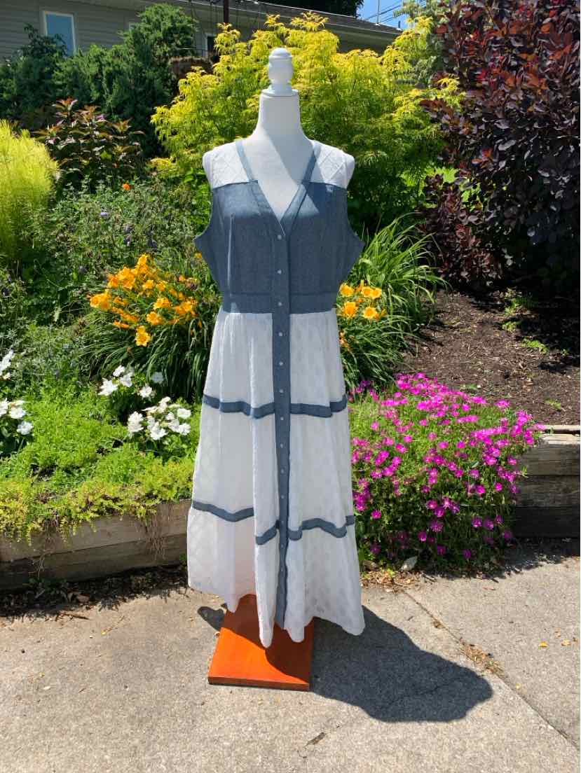 Sleeveless white sundress with blue horizontal stripes and button-down front on mannequin outdoors.