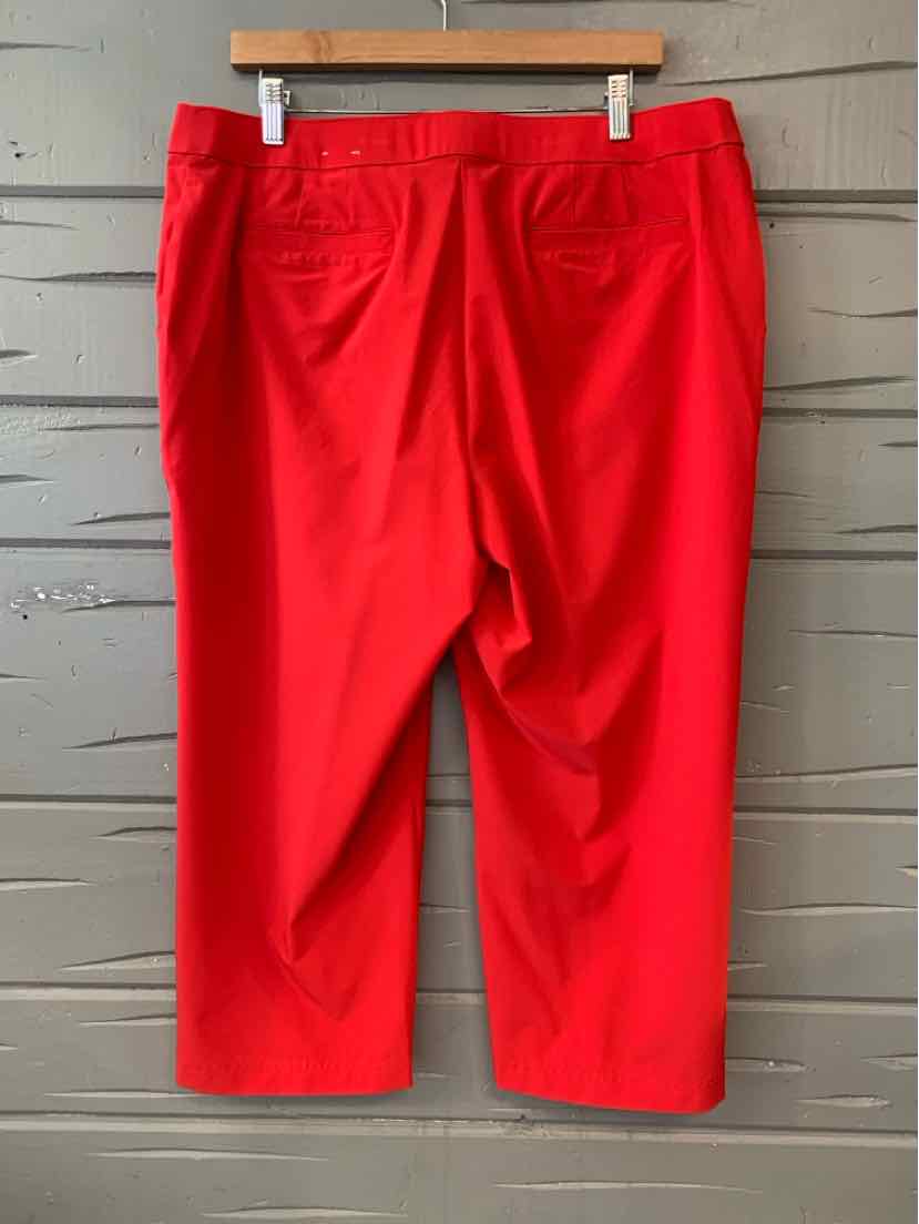 Bright red mid-length pants with back pockets, straight leg cut, hanging on wooden hanger.