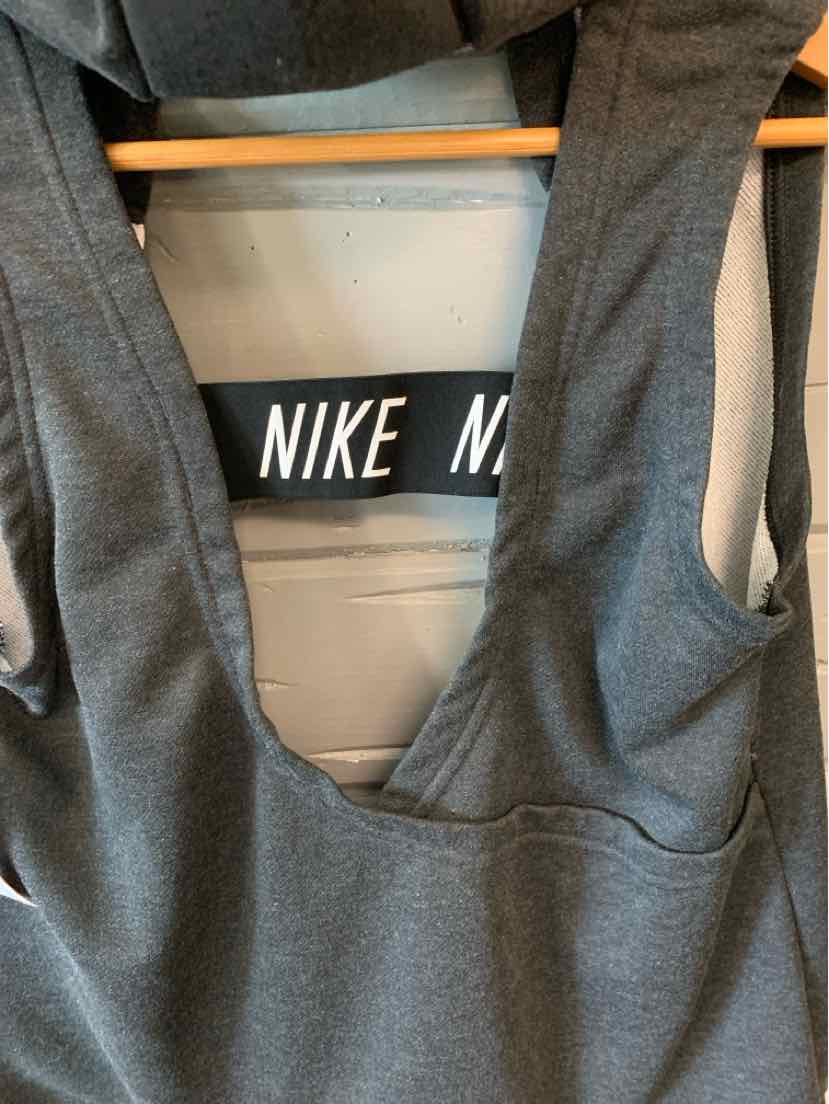 Gray sleeveless Nike athletic tank top with deep armholes and soft fabric hanging on a wooden hanger.