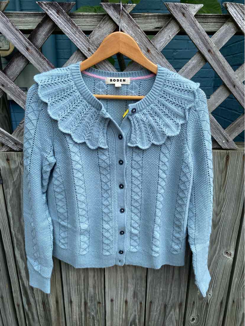 Light blue knit cardigan with scalloped collar, cable knit pattern, and front buttons.