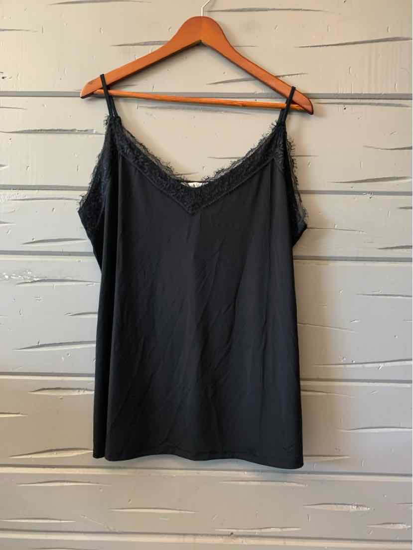 Black women's casual top with lace trim on a wooden hanger against white planked wall.