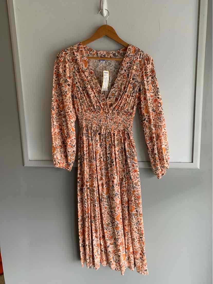 Orange floral midi dress with long sleeves, V-neckline, and pleated skirt on wooden hanger.