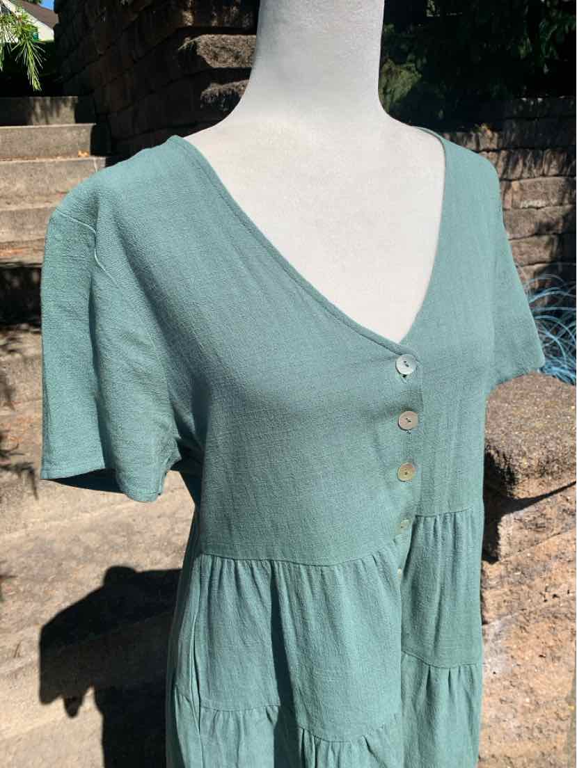 Light green short-sleeve blouse with V-neck, three front buttons, and gathered waist detail.
