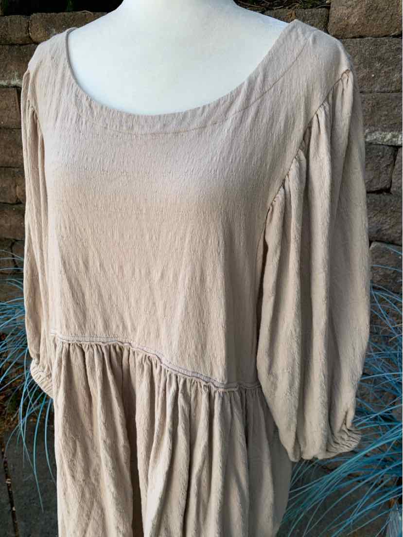 Beige long-sleeve dress with scoop neckline and gathered waist detail in lightweight fabric.