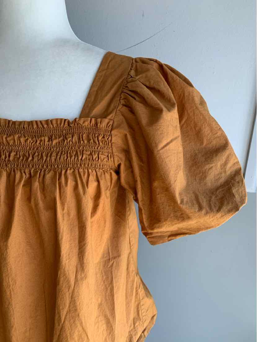 Tan cotton blouse with smocked square neckline and puffed short sleeves.
