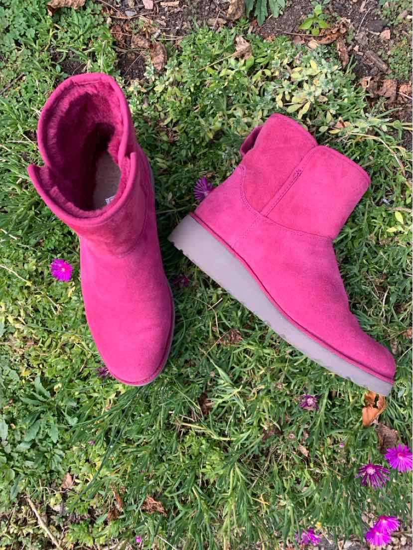 Bright pink suede mid-calf UGG boots with plush lining and thick gray soles, shown upright and on their side.