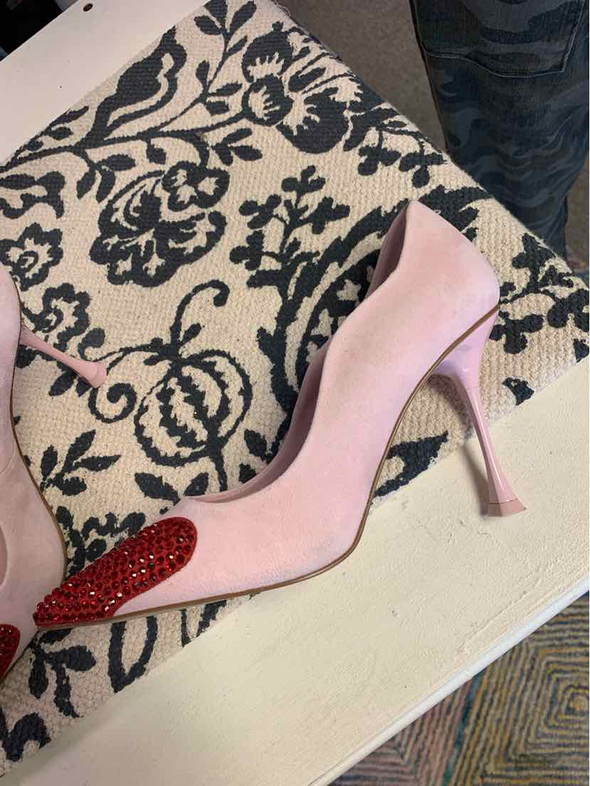 Pink suede high-heeled shoe with a pointed toe adorned with red rhinestones.