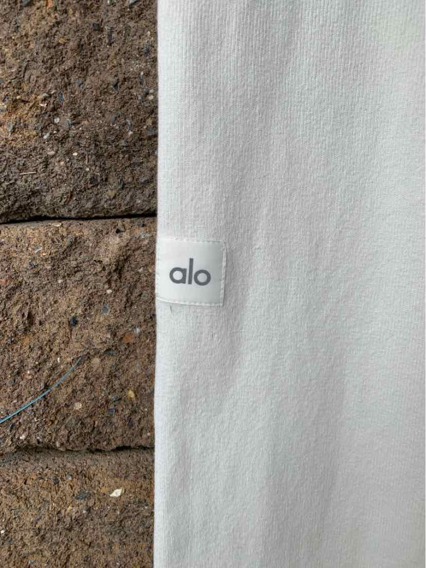 Close-up of white knit fabric with small white label featuring grey "alo" logo.