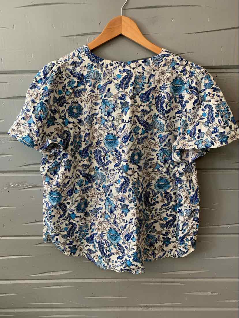 Blue and white floral short-sleeve blouse with round neckline, size XL, on wooden hanger.