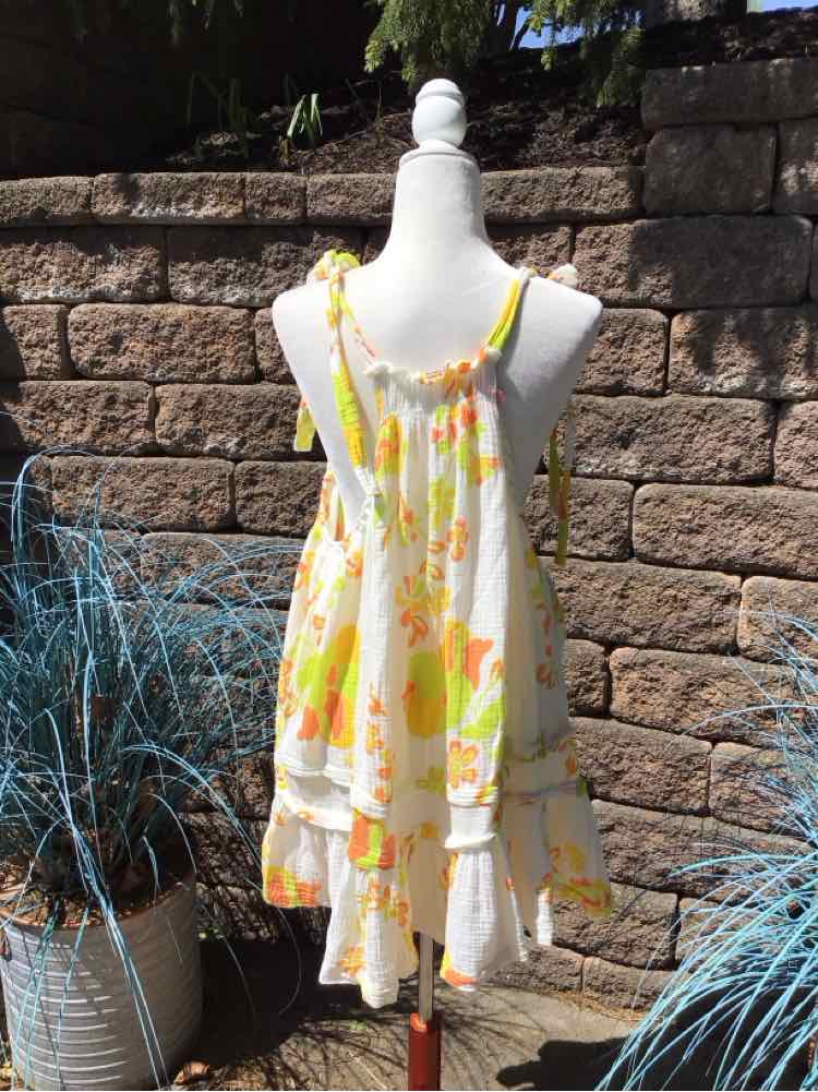 Yellow and white floral sundress with spaghetti straps and ruffled hem on mannequin.