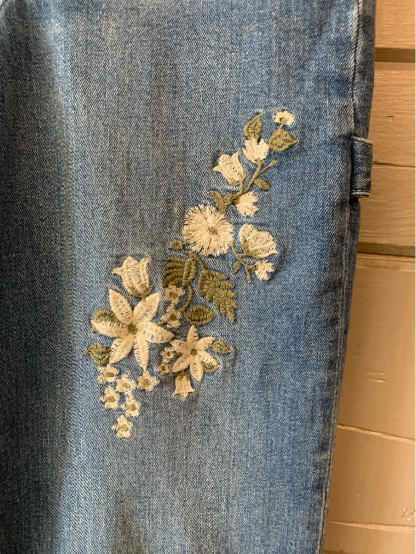 Light blue denim skirt with beige and white floral embroidery on front side.