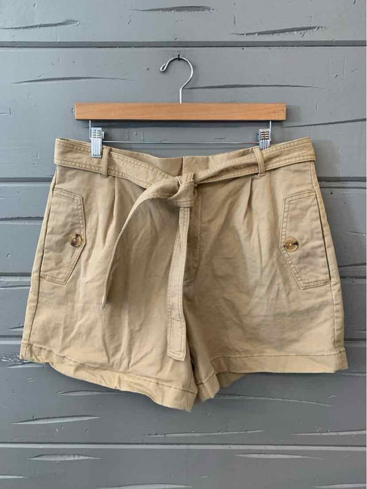 Khaki high-waisted shorts with front patch pockets and self-tie belt on wooden hanger.
