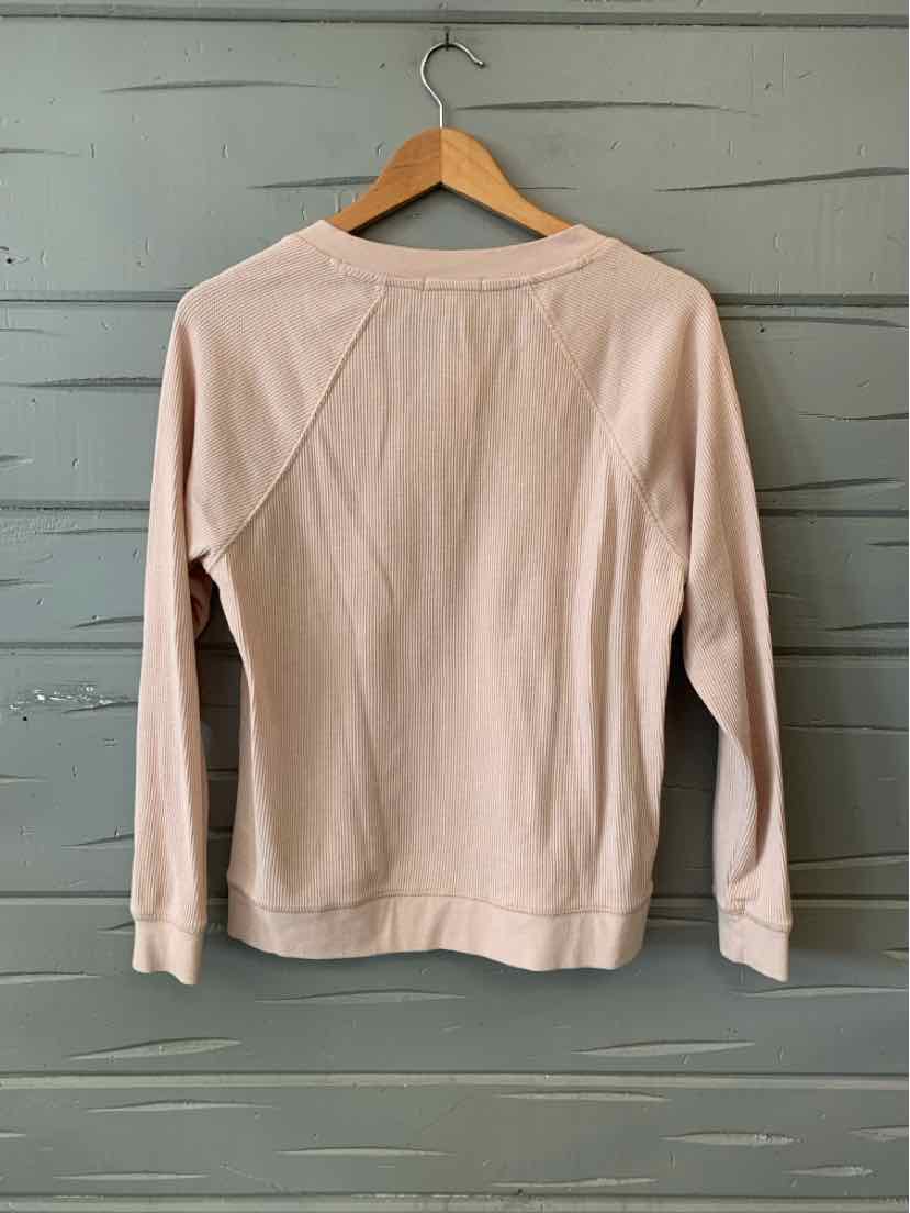 Light pink waffle-knit long-sleeve shirt with crew neck and raglan sleeves on wooden hanger.