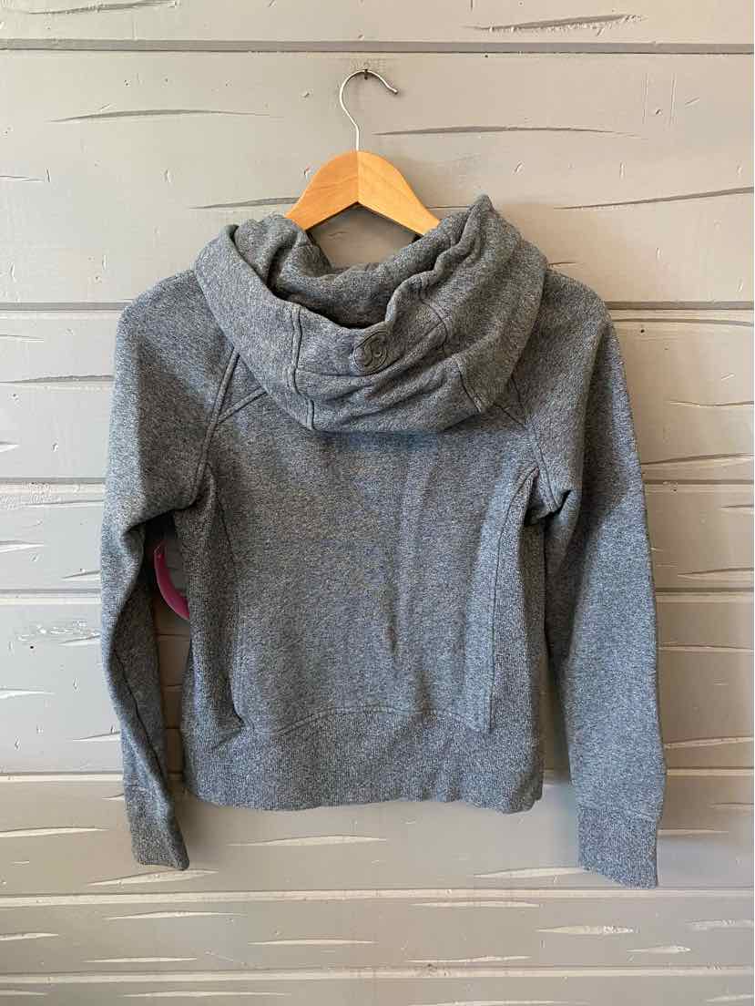 Heather gray long-sleeve hoodie with a fitted shape and soft fabric hanging on a wooden hanger against a white wooden wall.