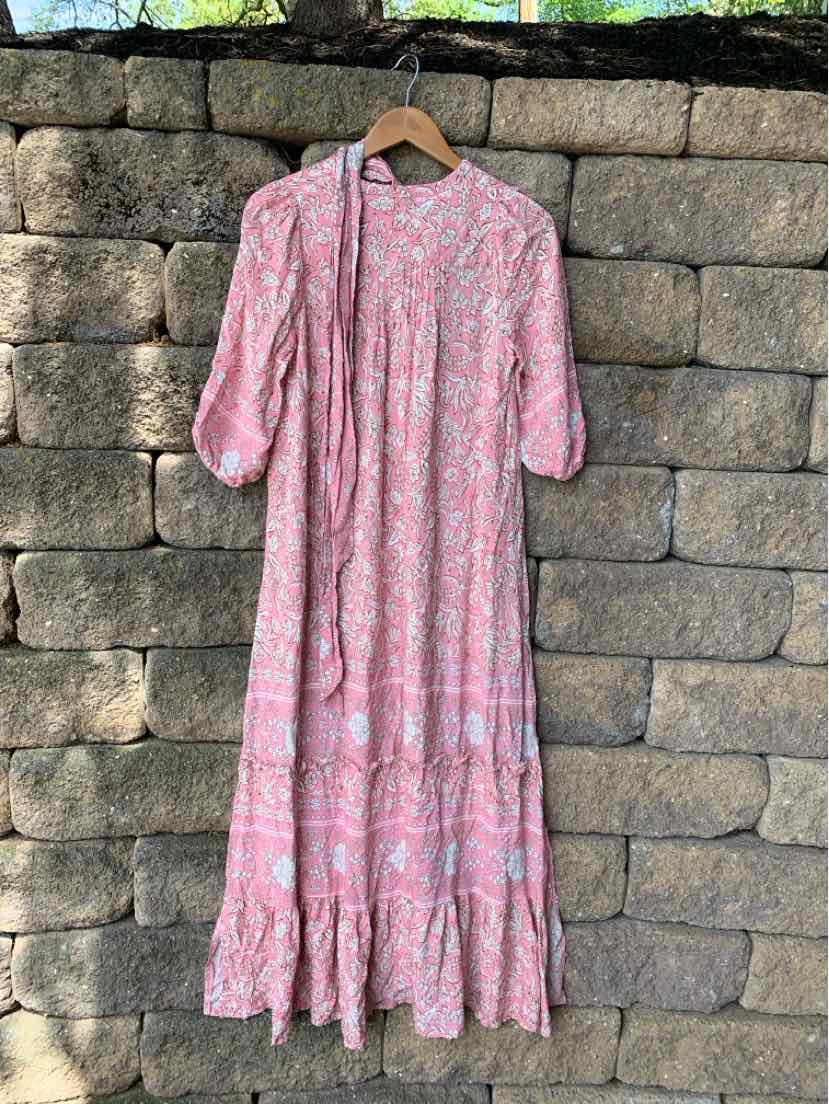 Pink floral midi dress with puff sleeves and tiered ruffle hem hanging on wooden hanger.