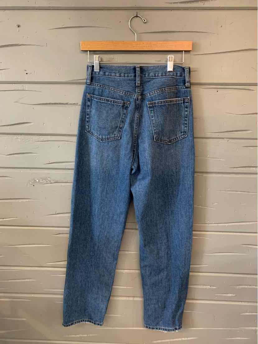 High-waisted blue denim jeans with a straight leg and rear patch pockets hanging on wooden hanger.