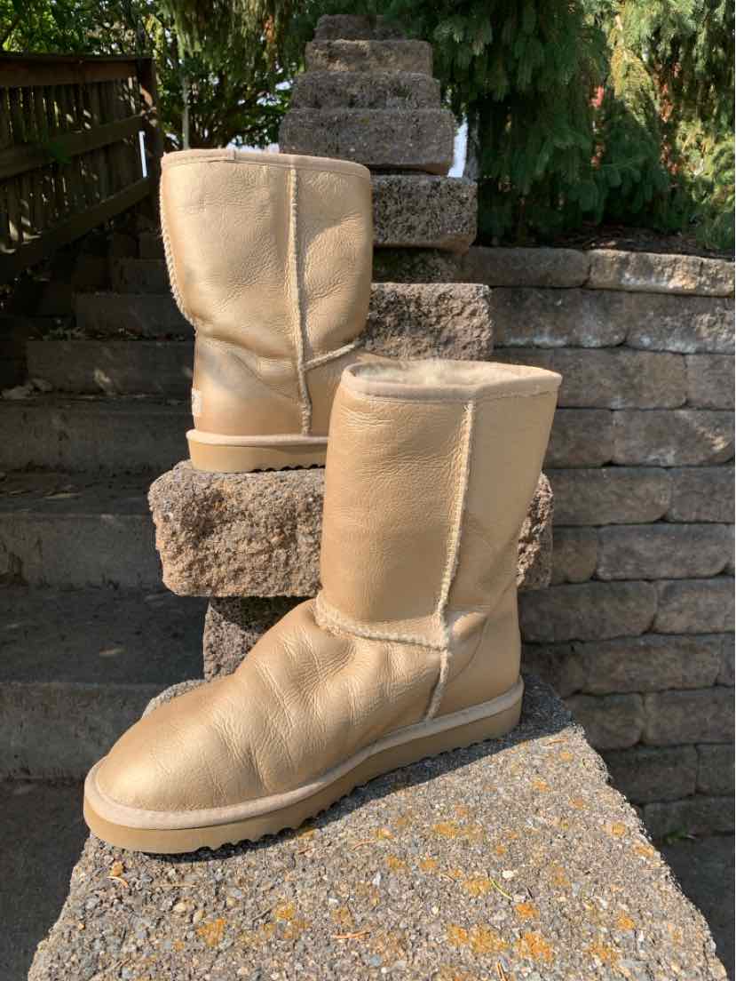 Pair of tan suede UGG boots with rounded toes, short shafts, and thick textured soles.