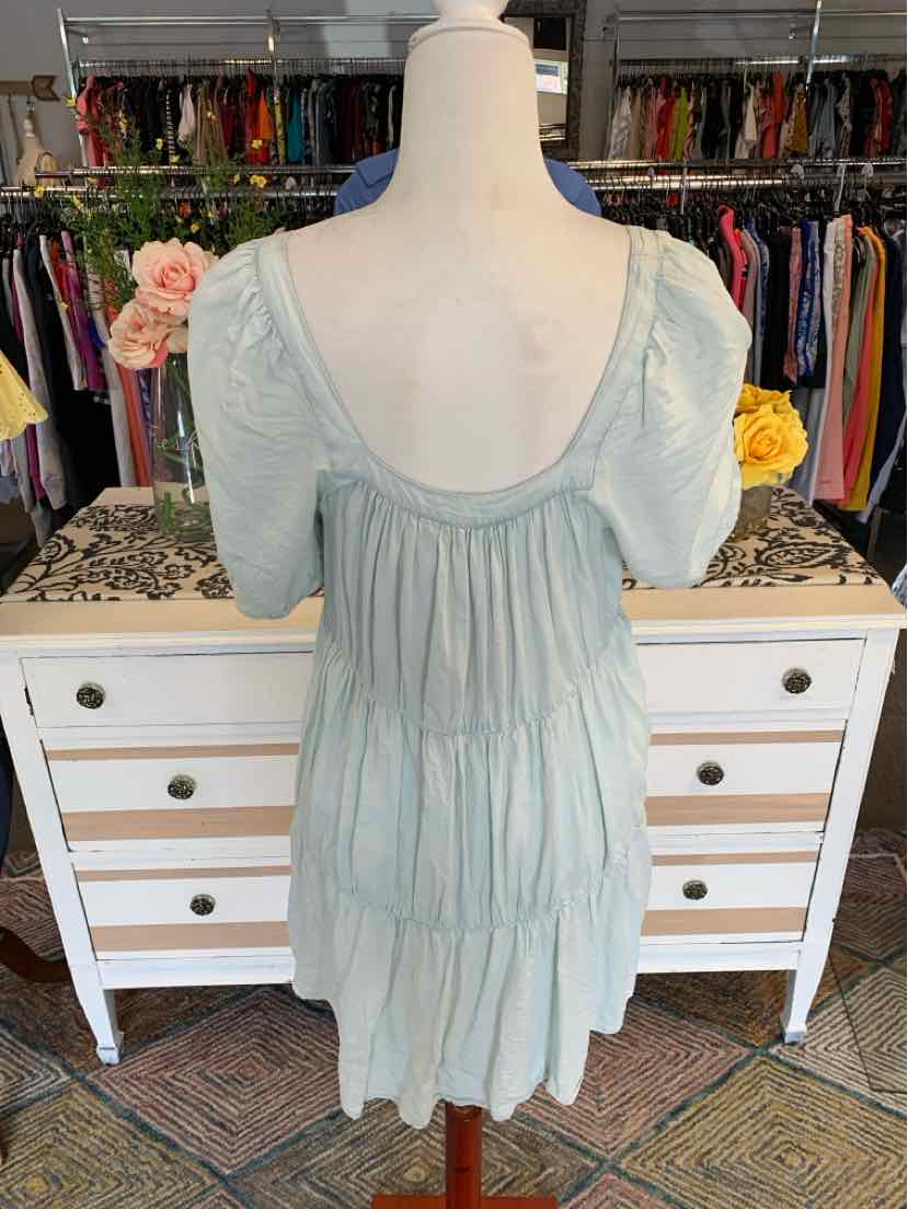Light green short-sleeve dress with smocked back and tiered skirt on mannequin.