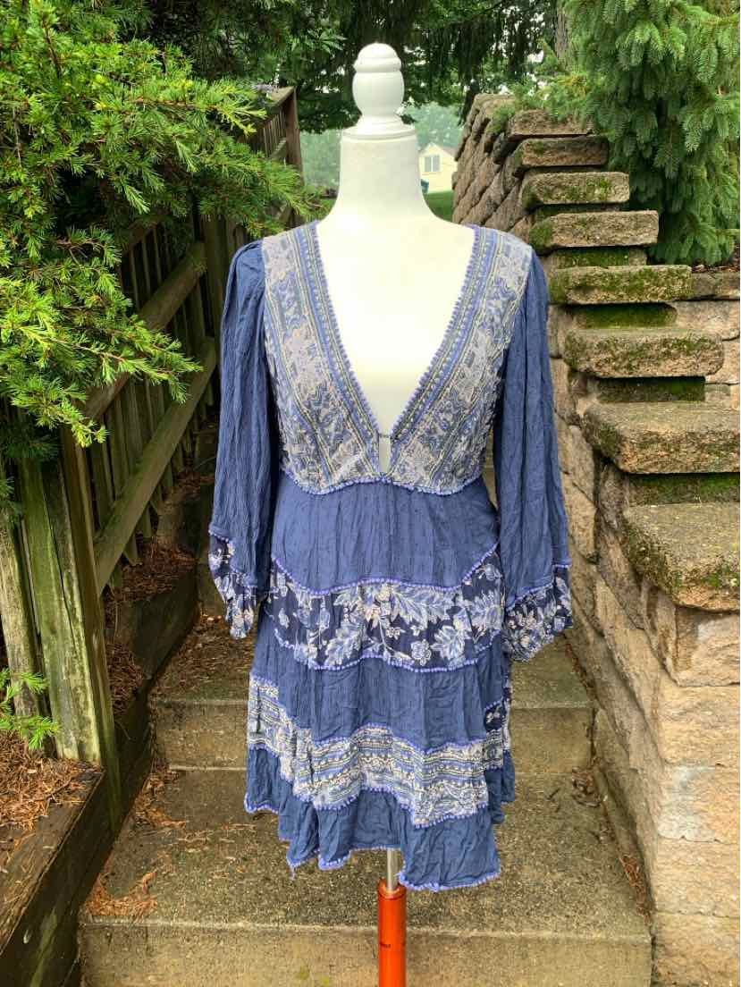 Blue bohemian dress with deep V-neck, lace panels, and long puffed sleeves on mannequin.