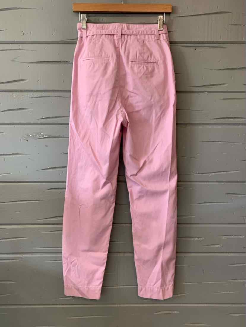 Light pink toddler pants with elastic waistband and back pockets hanging on wooden hanger.