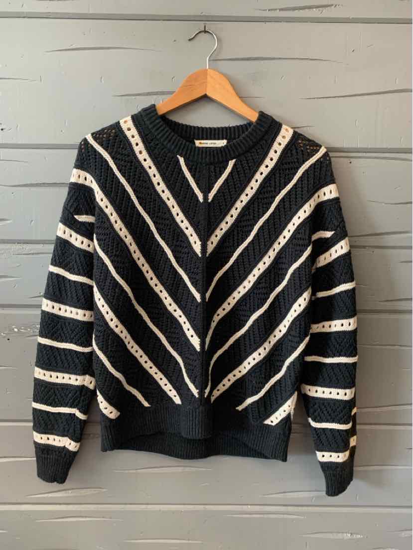 Black and white striped knit sweater with a round neckline and long sleeves on a wooden hanger.
