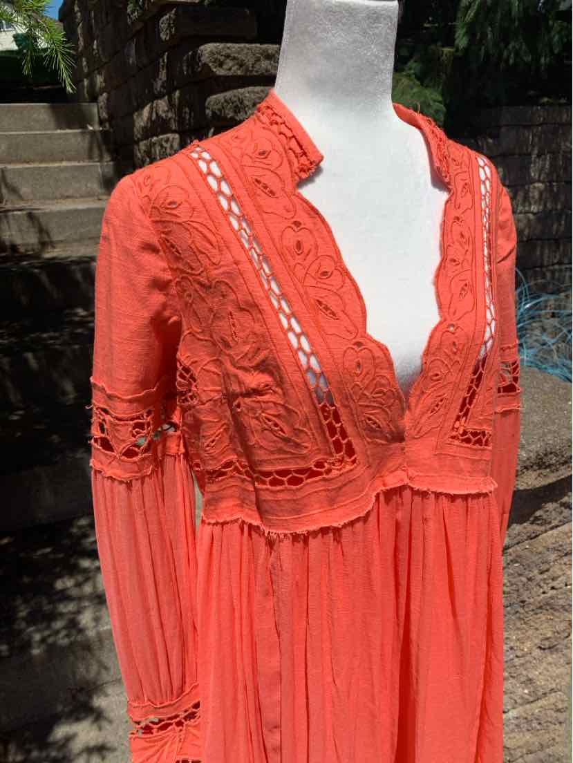 Coral long-sleeve dress with lace detailing, scalloped neckline, and gathered waist.