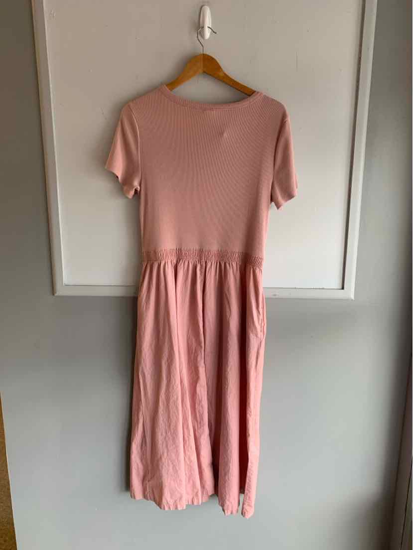 Soft pink short-sleeve dress with a fitted ribbed bodice and gathered waist on wooden hanger.