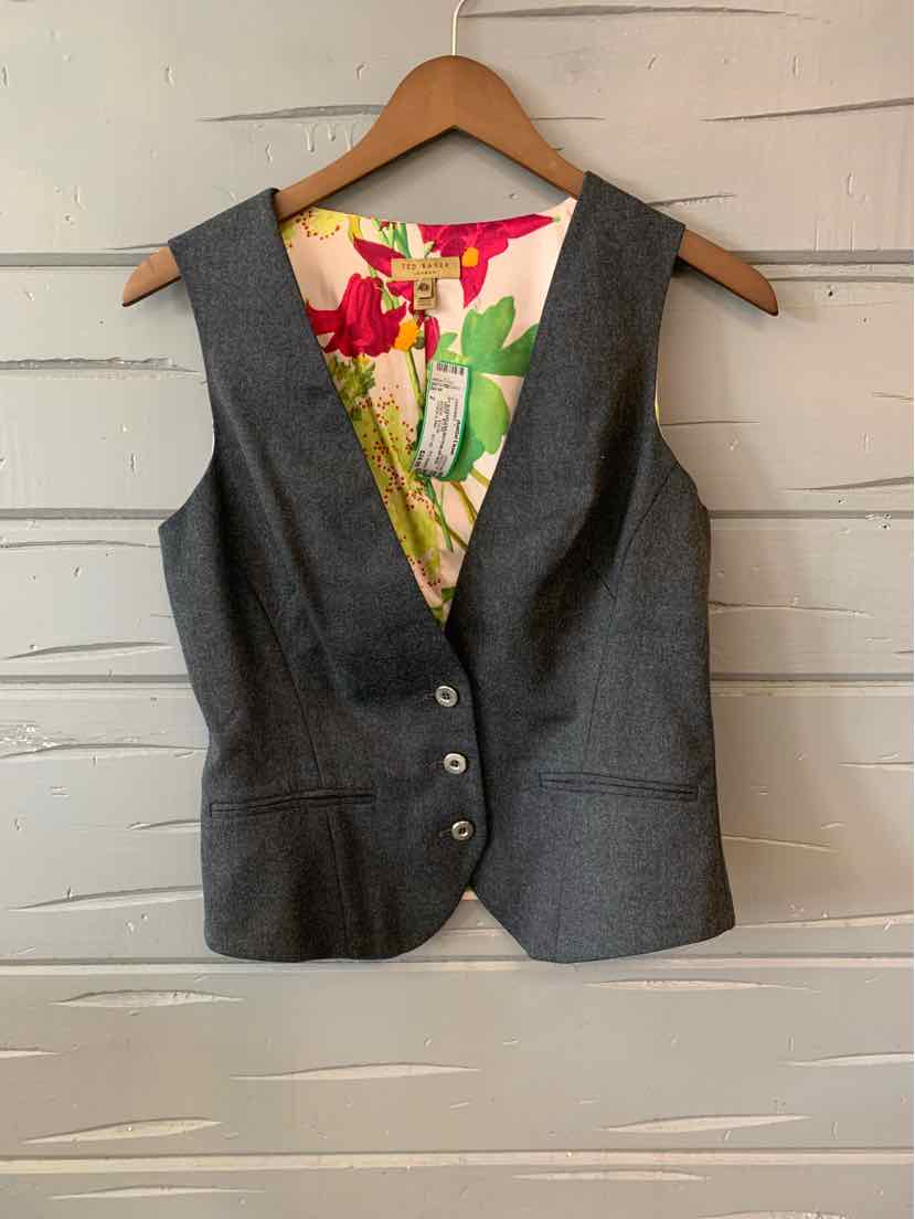 Grey sleeveless vest with three buttons and a colorful floral inner lining hanging on wooden hanger.