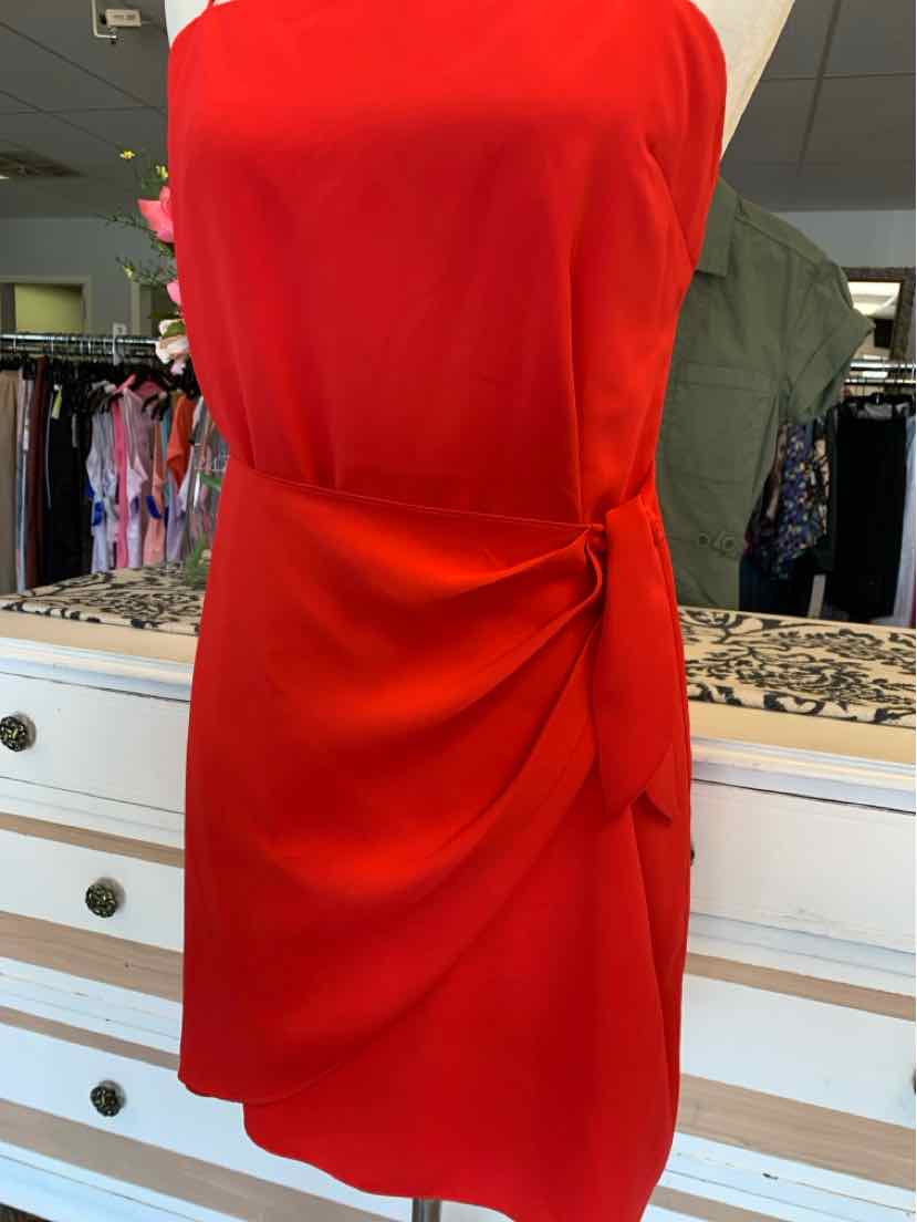 Red sleeveless dress with side tie detail and knee-length hem on mannequin.