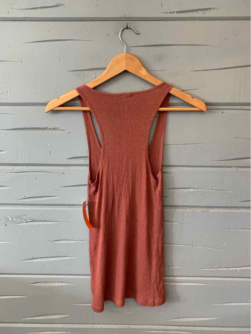 Rust-colored sleeveless tank top with scoop neckline and racerback, hanging on wooden hanger.