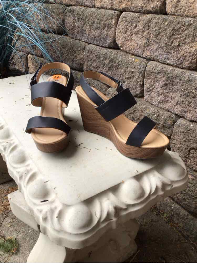 Black wedge sandals with two wide straps and a tan platform sole, size 11.