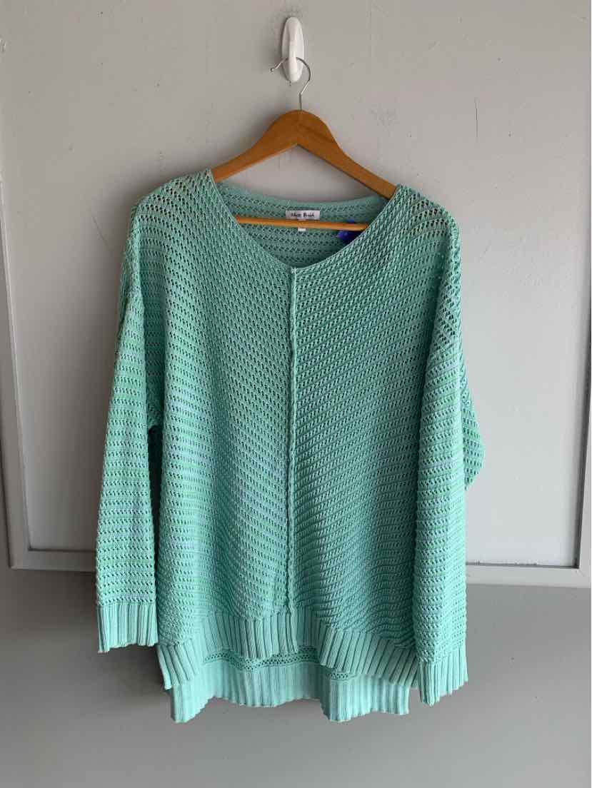 Light blue knit sweater with ribbed cuffs and hem hanging on wooden hanger against white door.