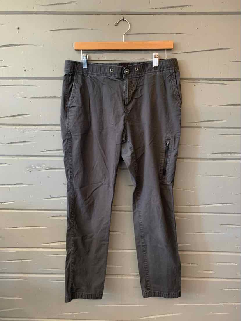Dark gray Vuori women’s straight-leg pants with a button closure, belt loops, and side pockets, hanging from a wooden hanger.