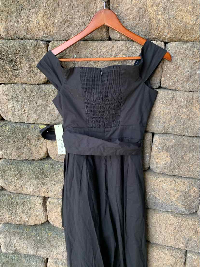 Black off-shoulder fitted dress with ruched bodice and knee-length skirt on wooden hanger.