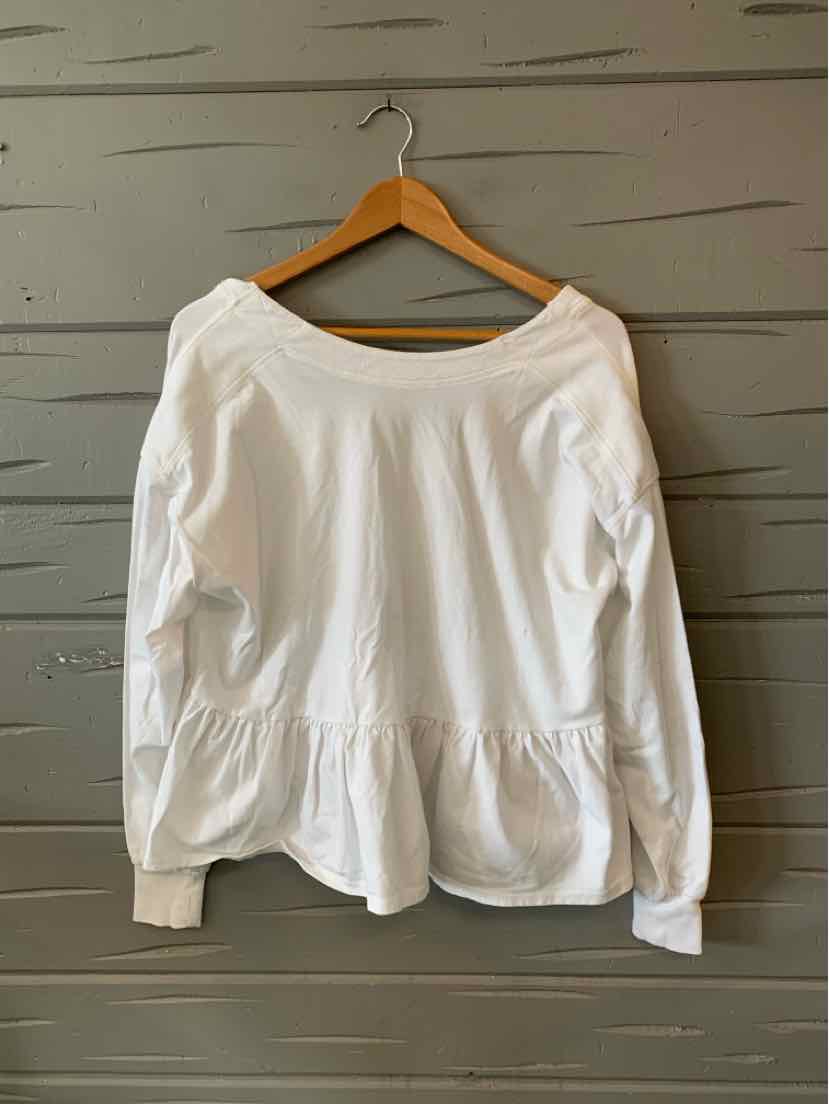 White long-sleeve blouse with peplum hem and boat neckline hanging on wooden hanger.