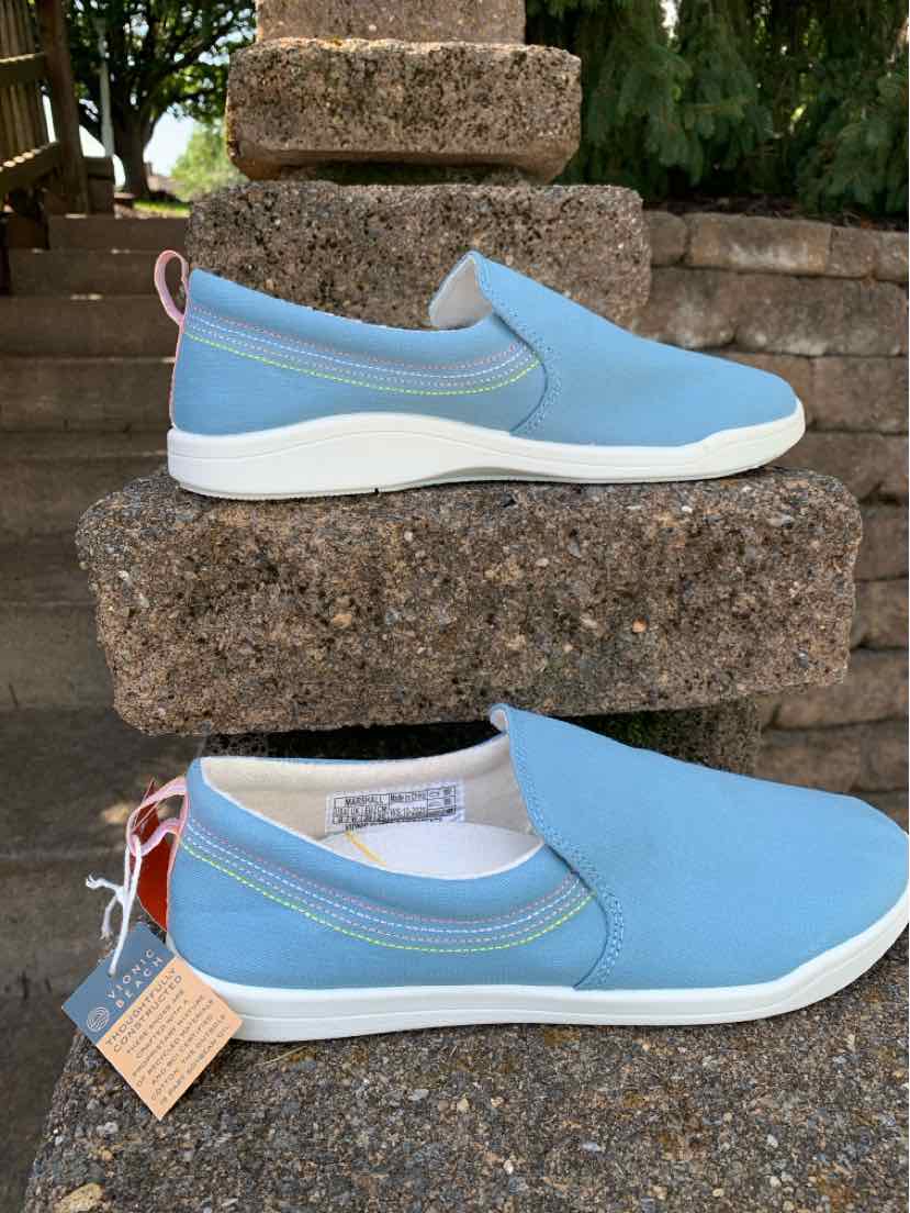 Light blue slip-on sneaker with white sole, rounded toe, and pull tab at heel.