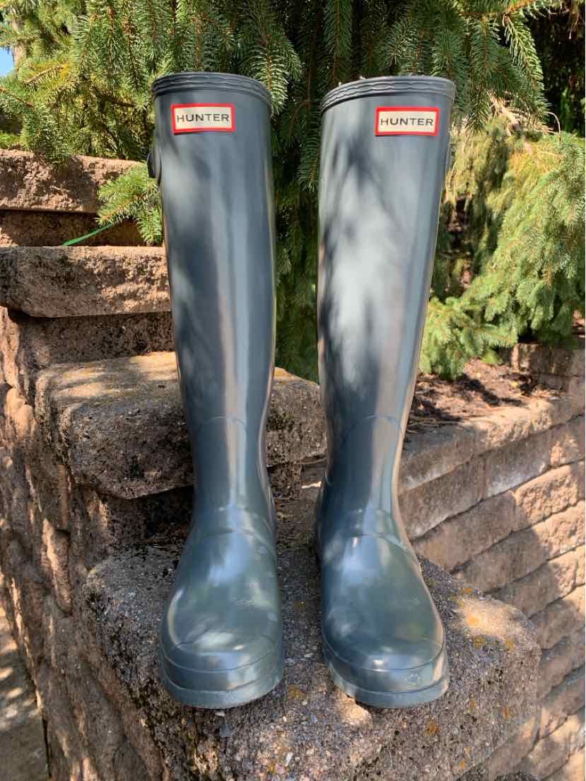 Gray tall rubber rain boots with rounded toes, flat soles, and red Hunter logo on front shafts.