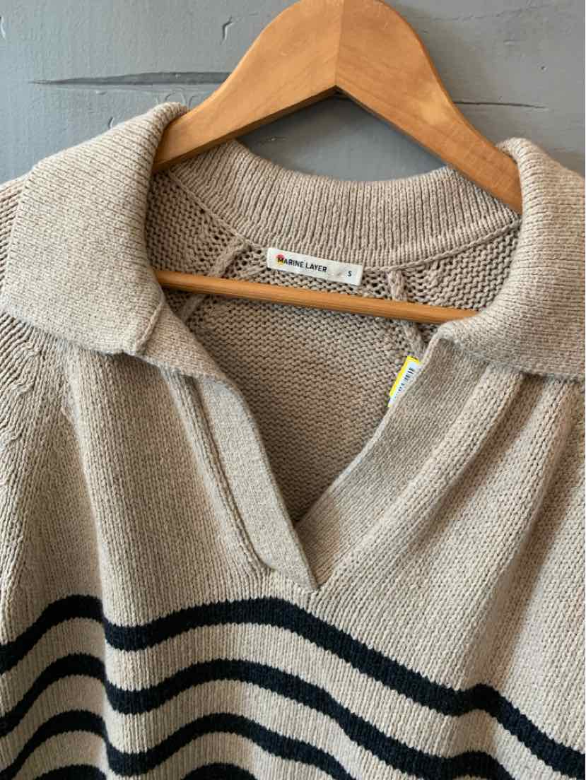 Beige knit marine layer sweater with navy horizontal stripes and a collared neckline on a wooden hanger.