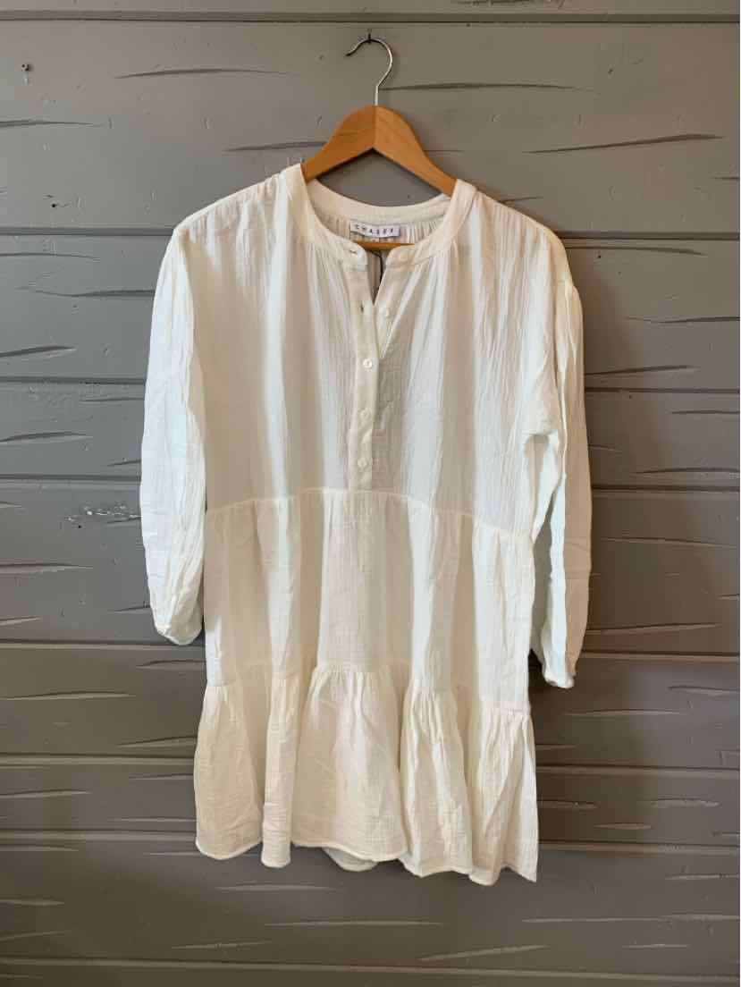 White long-sleeve loose dress with a round neckline and tiered hem hanging on wooden hanger.